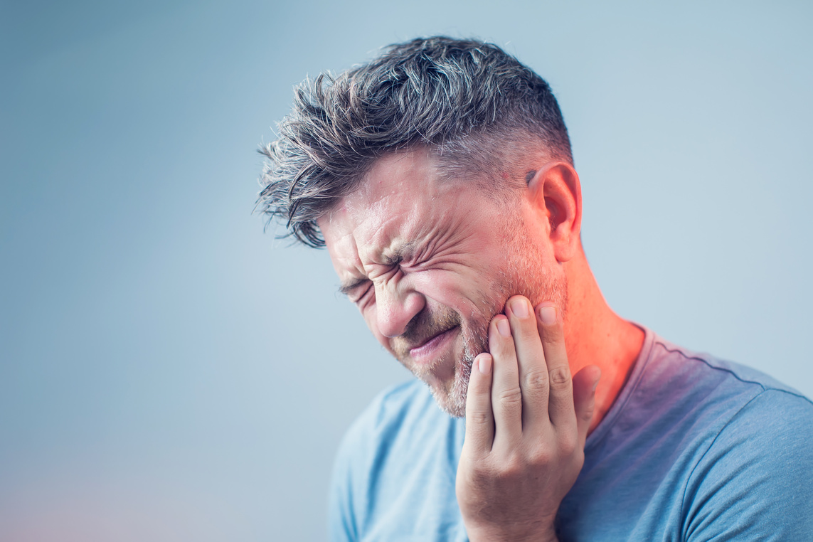 Toothache, medicine, health care concept, Teeth Problem, young m Man experiencing severe tooth pain holding his jaw, emergency dental care available at The Center for Complete Healthy Dentistry in Wilton, CT