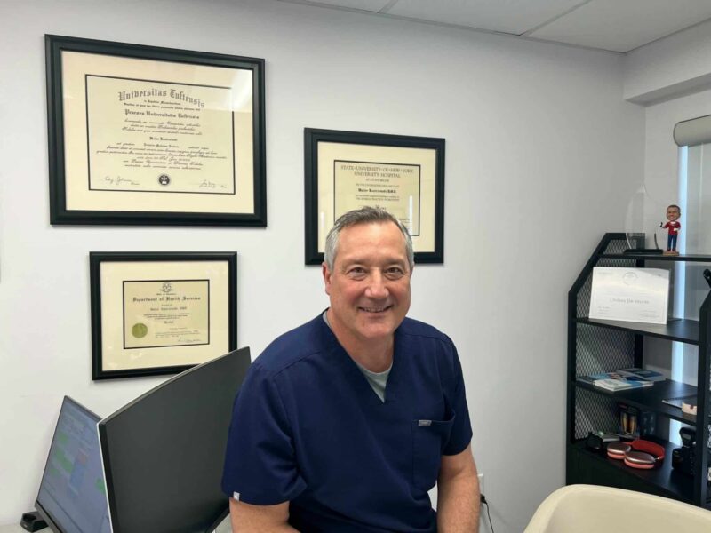 dr-walter-kostrzewski-dmd-dentist-center-for-complete-healthy-dentistry-wilton-ct Dr. Walter Kostrzewski, DMD, smiling in his office with dental credentials and diplomas, award-winning cosmetic dentist at The Center for Complete Healthy Dentistry in Wilton, CT