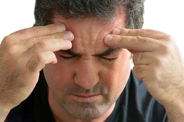 Man suffering from migraine headache holding temples, NTI-tss migraine relief treatment available at The Center for Complete Healthy Dentistry in Wilton, CT